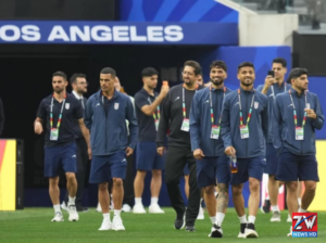 Iran national football team arriving at an airport in the United States ahead of their FIFA World Cup match, with players carrying bags and team gear amid heightened media attention.